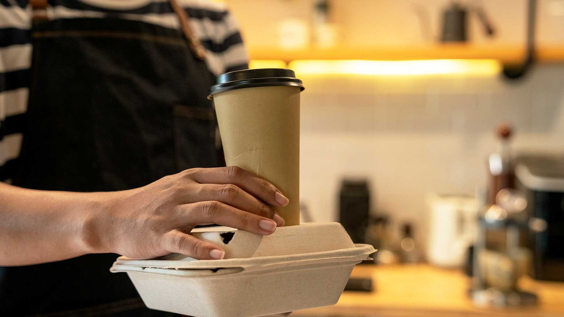 Personal serverar varm dryck och mat i takeaway-förpackningar 